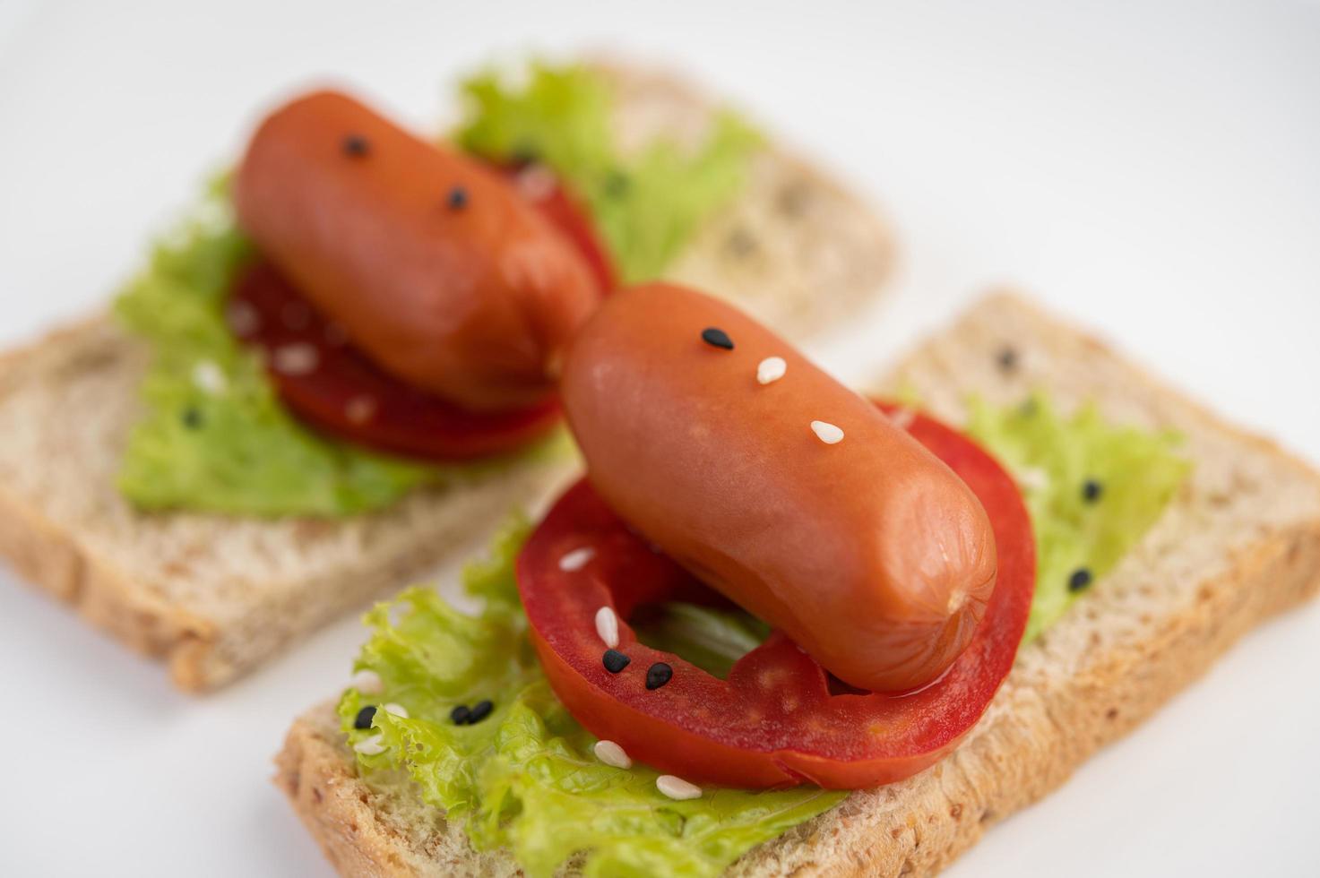 Wurst mit Tomaten und Salat auf Brot foto