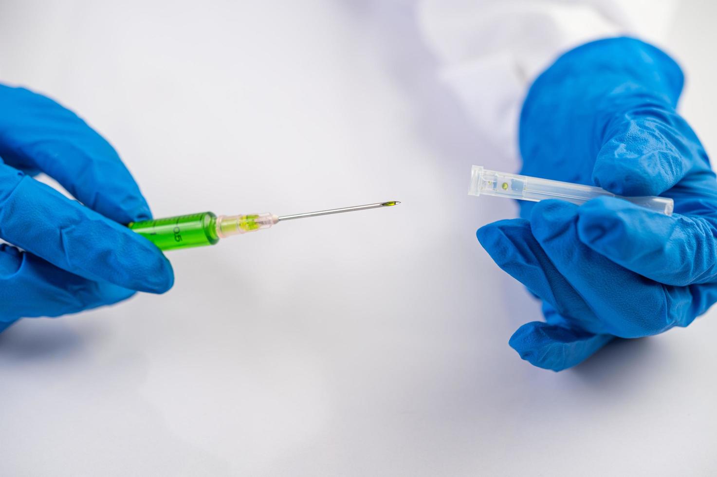 Wissenschaftler tragen Handschuhe, die eine Spritze mit einem Impfstoff halten, um Covid-19 zu verhindern foto