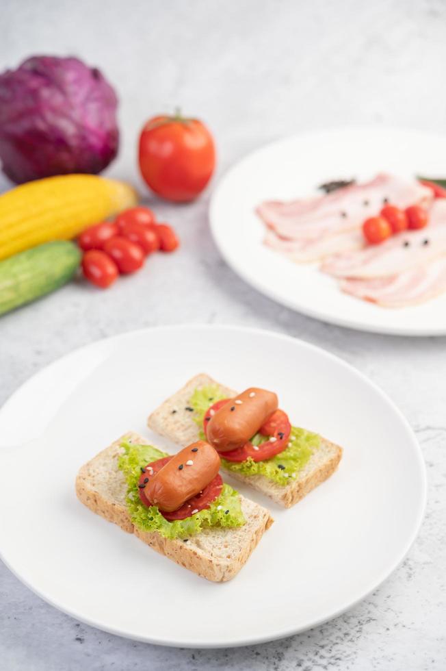 Wurst mit Tomaten und Salat auf Brot foto