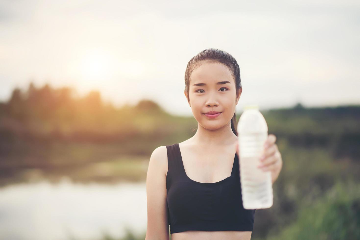 junger Fitness-Teenager, der Wasserflasche nach laufender Übung hält foto