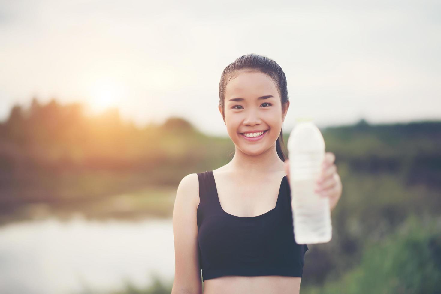 junger Fitness-Teenager, der Wasserflasche nach laufender Übung hält foto