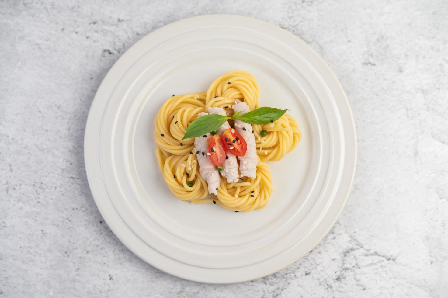 überzogene Spaghetti und Schweinefleisch auf einem weißen Teller angeordnet foto