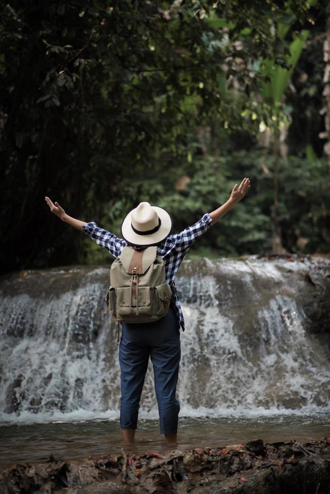 junge Frau, die Spaß unter einem Wasserfall im Wald hat foto