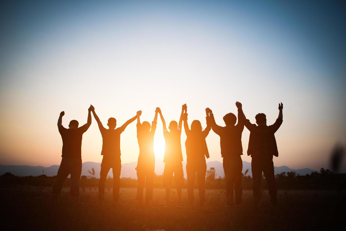 Silhouette des glücklichen Teams, das hohe Hände macht foto