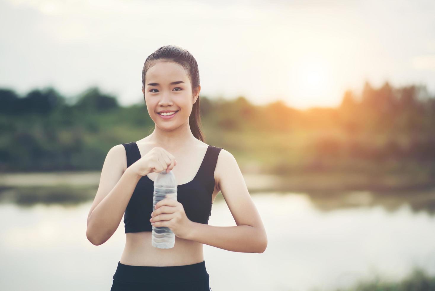 junger Fitness-Teenager, der Wasserflasche nach laufender Übung hält foto