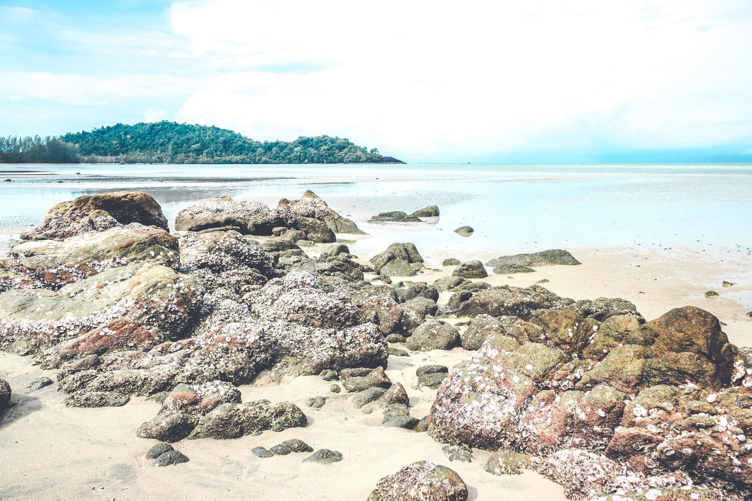 Felsen am Strand mit bewölktem blauem Himmel foto