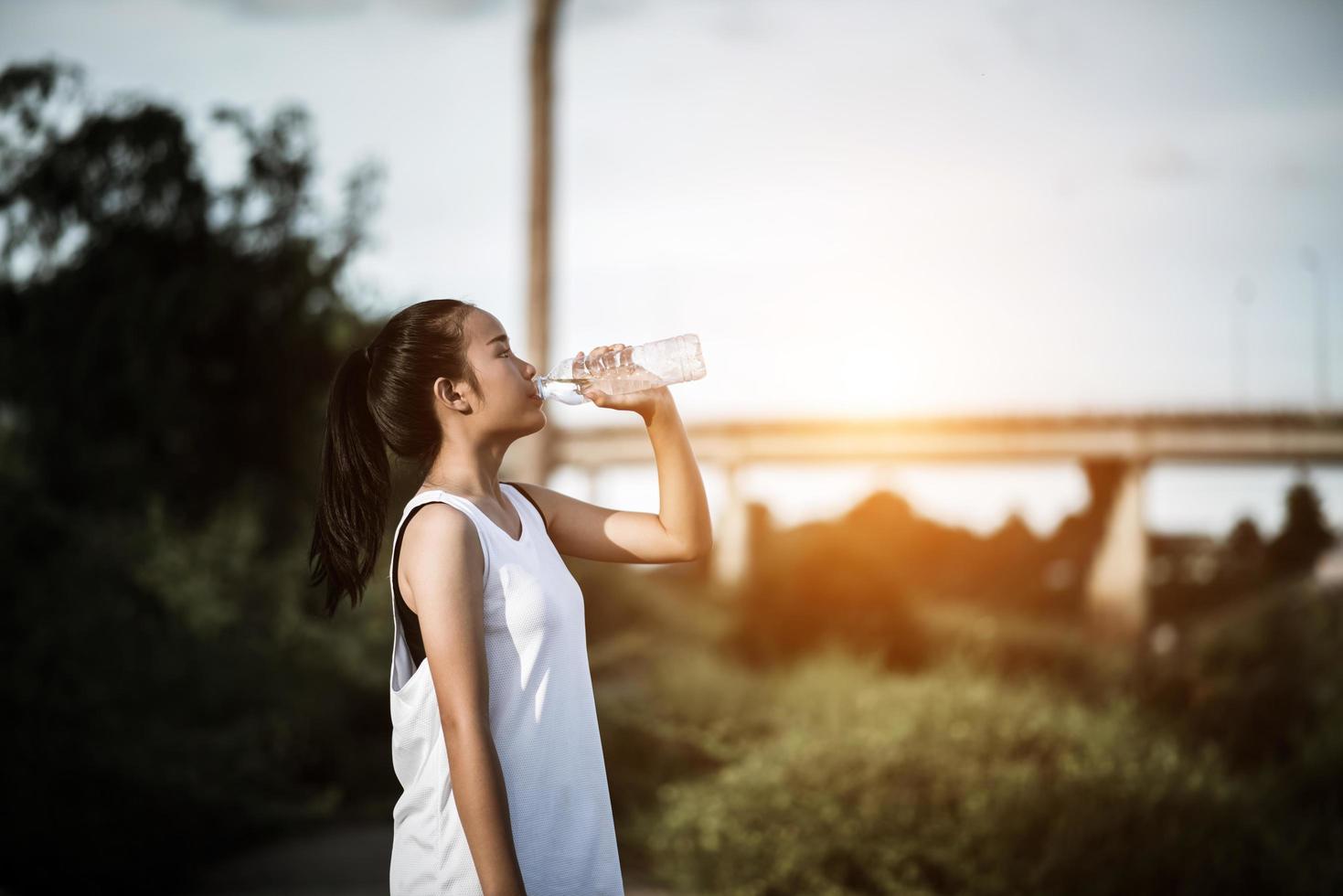 Trinkwasser des jungen Fitness-Teenagers nach laufender Übung foto