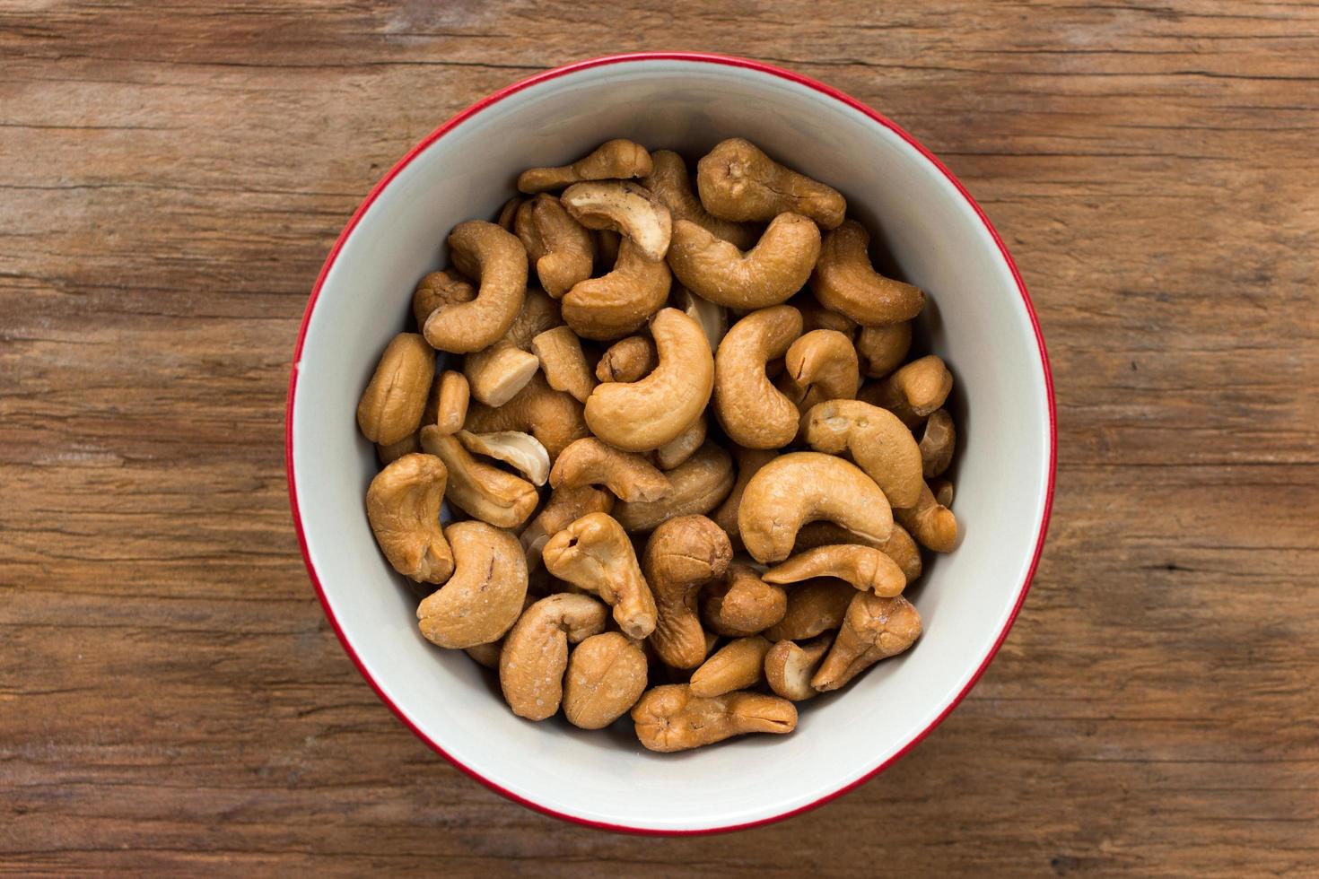 Cashewnüsse in weißer Schüssel auf Holztisch foto