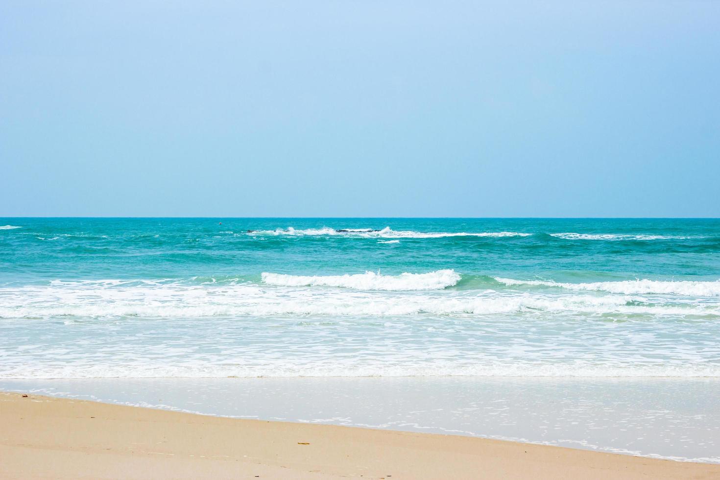 Sand und Wasser am Strand mit klarem blauem Himmel foto