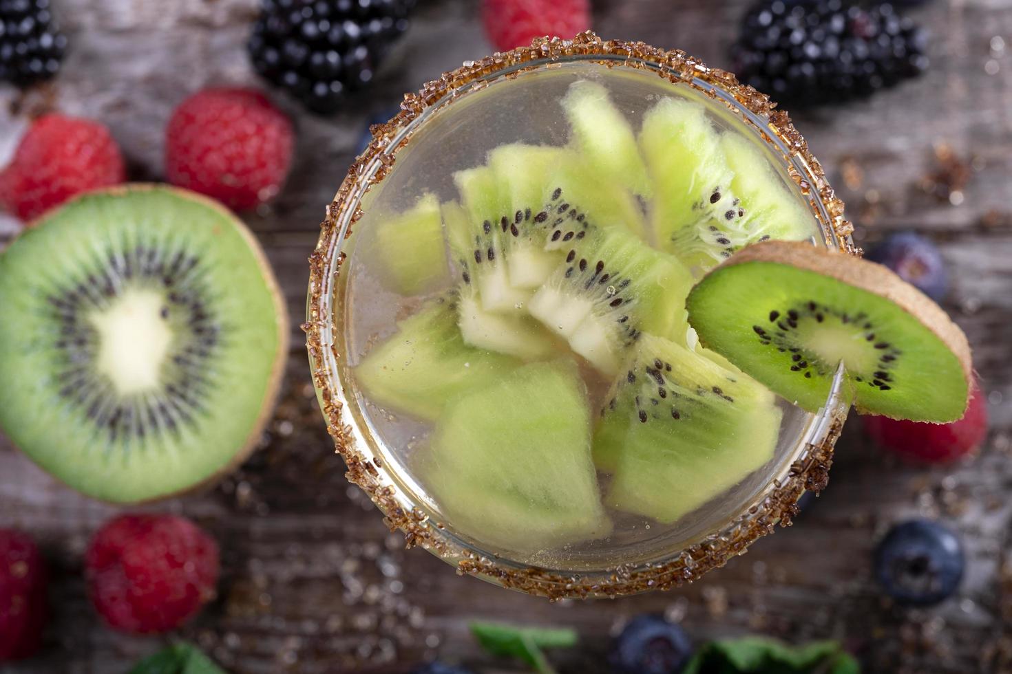 Kiwi-Cocktail von oben gesehen verziert mit Früchten des Waldes auf einem hölzernen Hintergrund foto