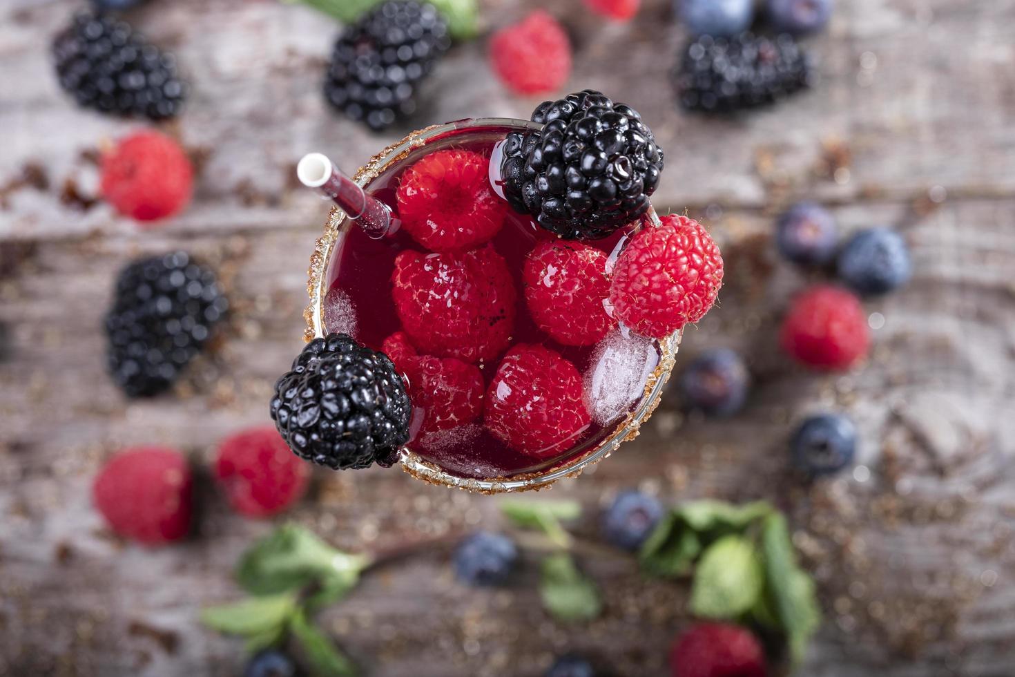 Waldfruchtcocktail in einem Glas von oben gesehen auf einem mit Brombeeren verzierten Holzsockel foto