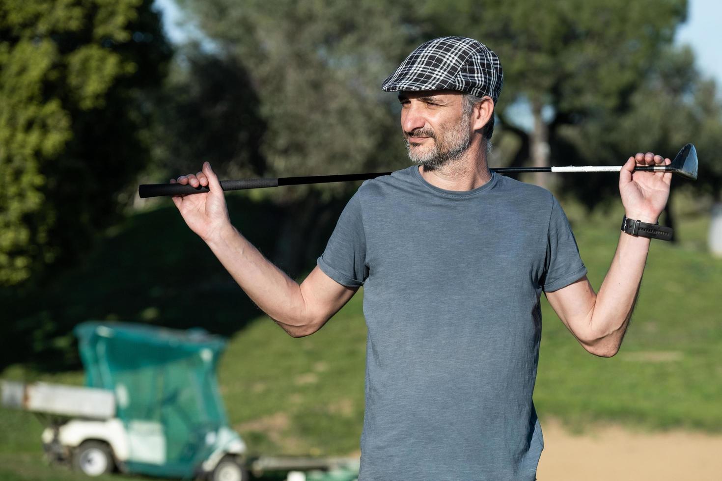 Golfspieler mit einer Kappe, die einen Golfschläger auf seinem Rücken hält foto