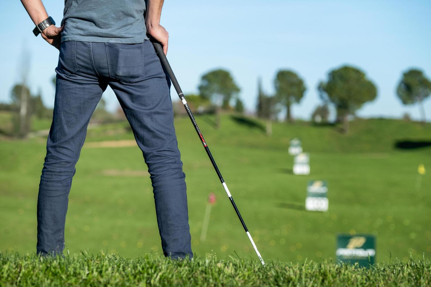 Golfspieler mit Kappe, die auf einen Golfschläger stützt, der den Platz betrachtet foto