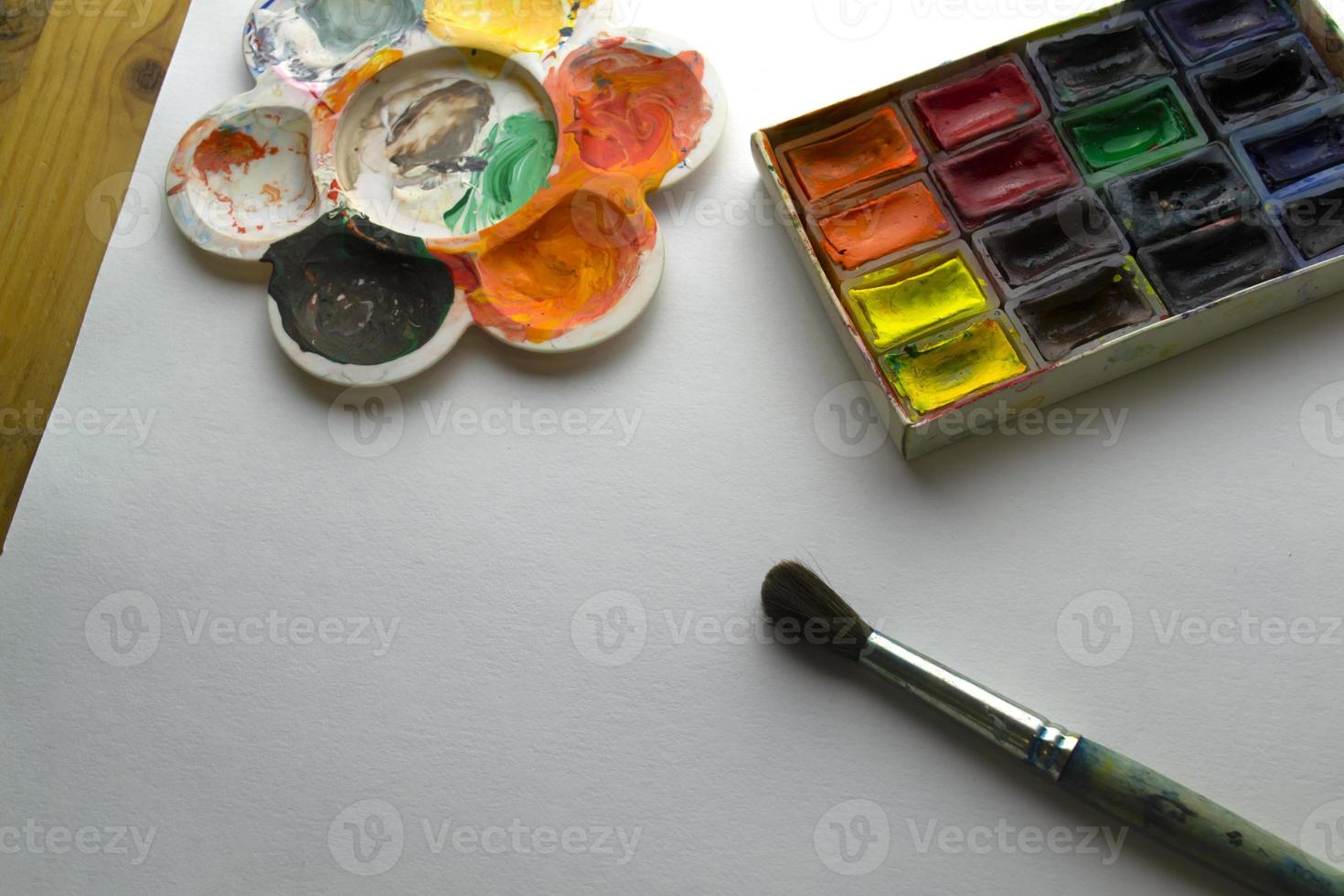 Farben, Pinsel, Palette und Papier auf dem Tisch. foto