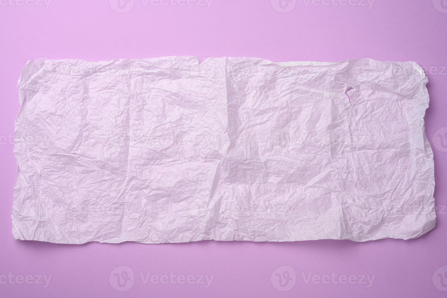 rechteckiges, zerknittertes Blatt Papier in Gewebe auf violettem Hintergrund foto