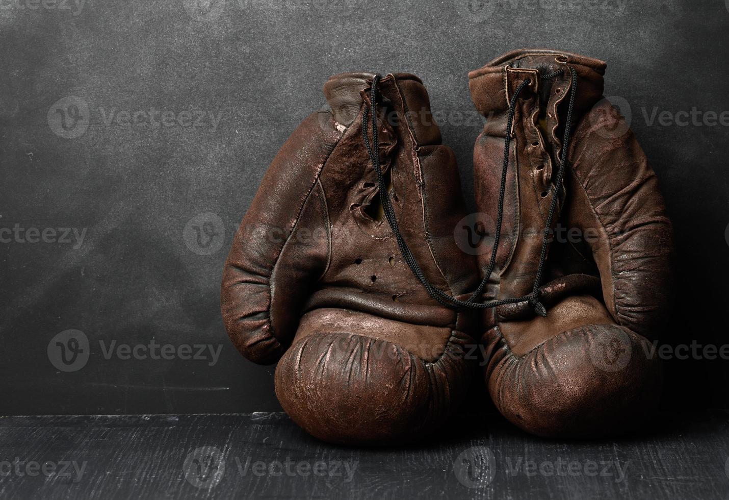 Vintage Boxhandschuhe aus braunem Leder auf schwarzem Hintergrund foto