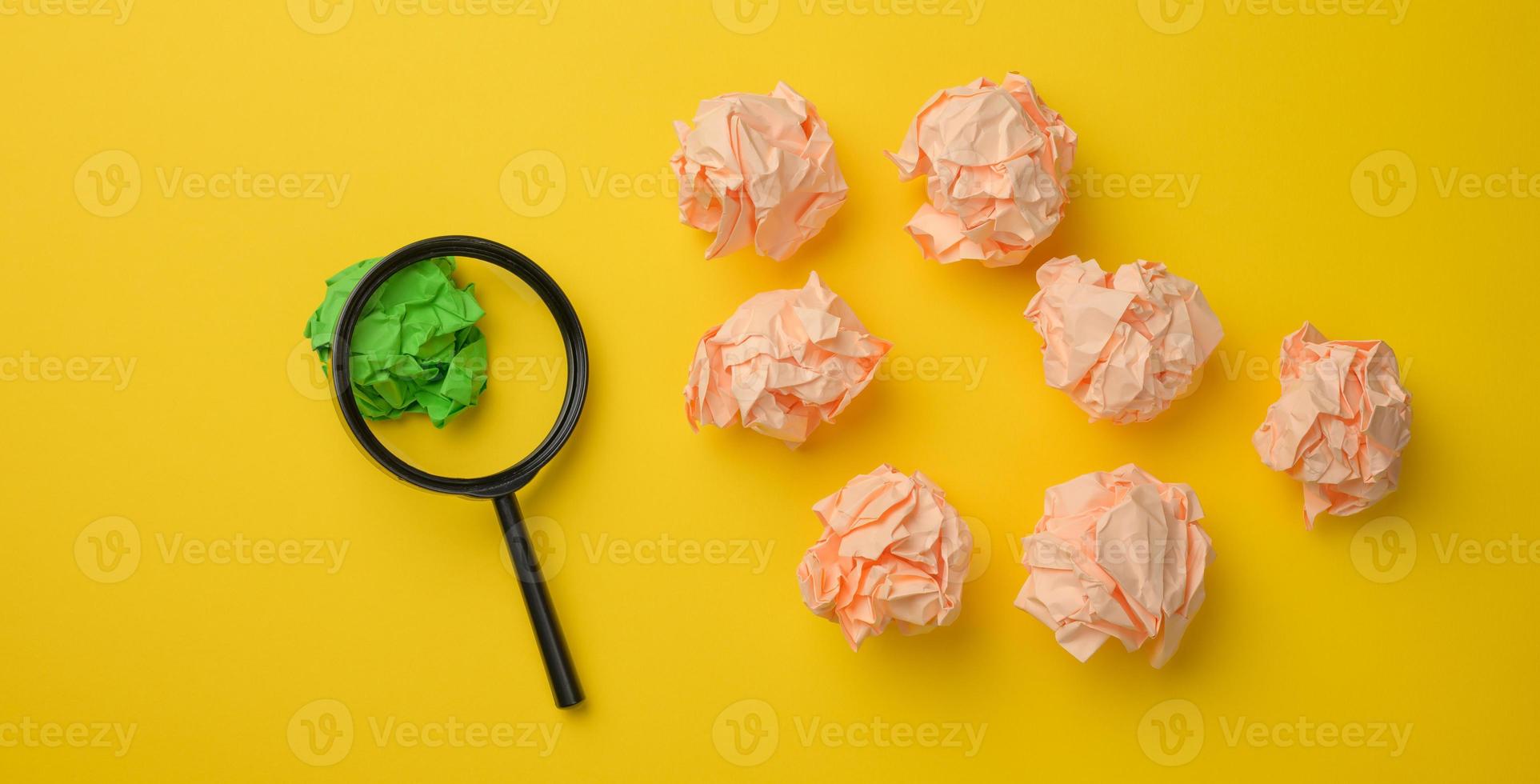 zerknitterte papierkugeln und schwarze plastiklupe auf gelbem hintergrund. Konzept der Suche nach Ideen und Lösungen, verschiedene Optionen foto