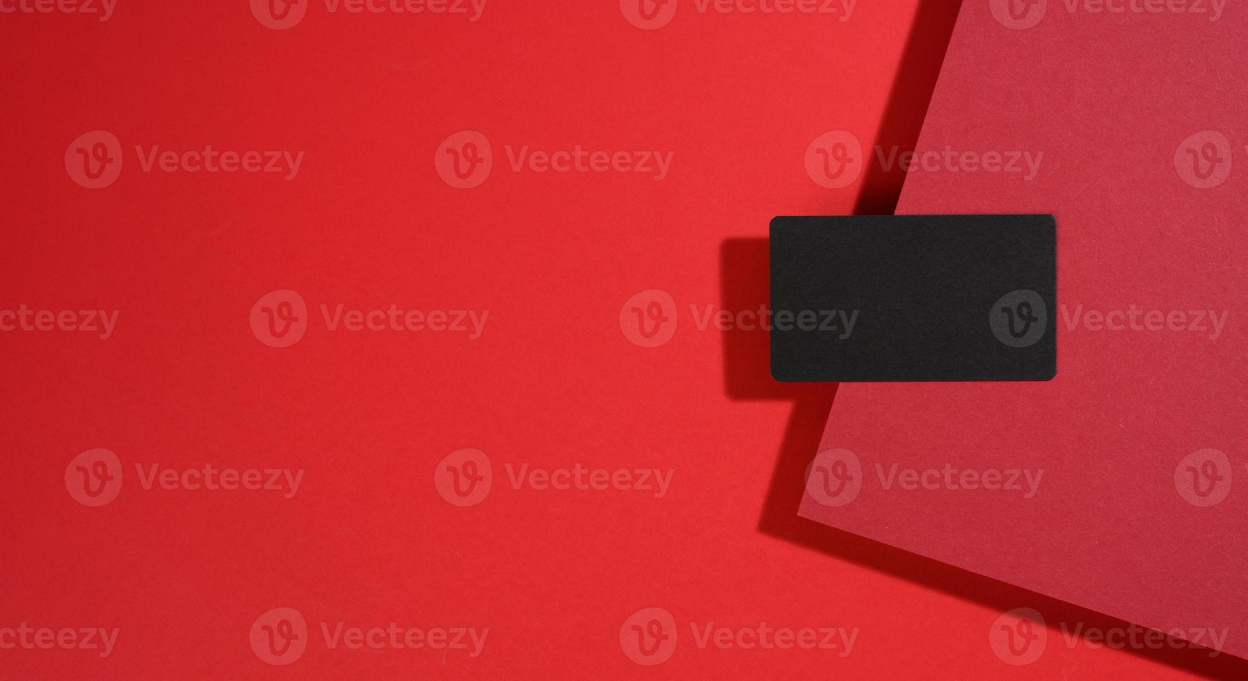 leere schwarze rechteckige visitenkarte liegt auf einem modernen roten hintergrund mit roten blättern papier mit einem schatten. Geschäftsvorlage foto
