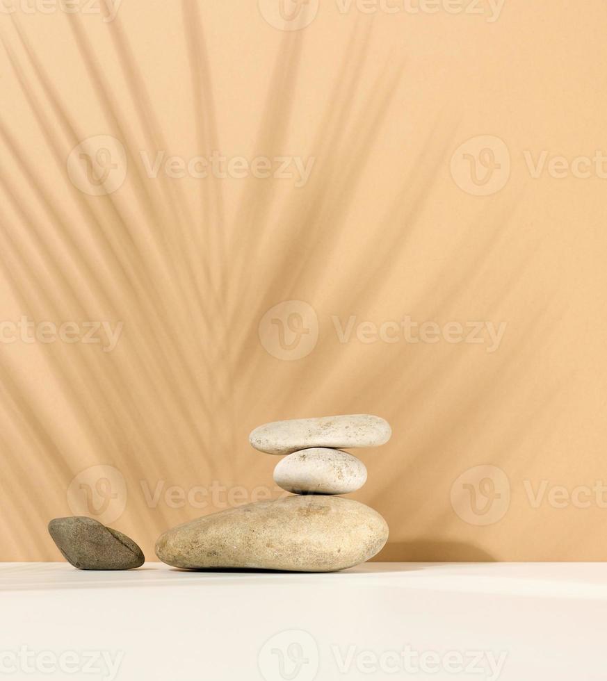 Stapel runder Steine und und der Schatten eines Palmblattes auf beigem Hintergrund. szene für vorführung von kosmetischen produkten, werbung foto