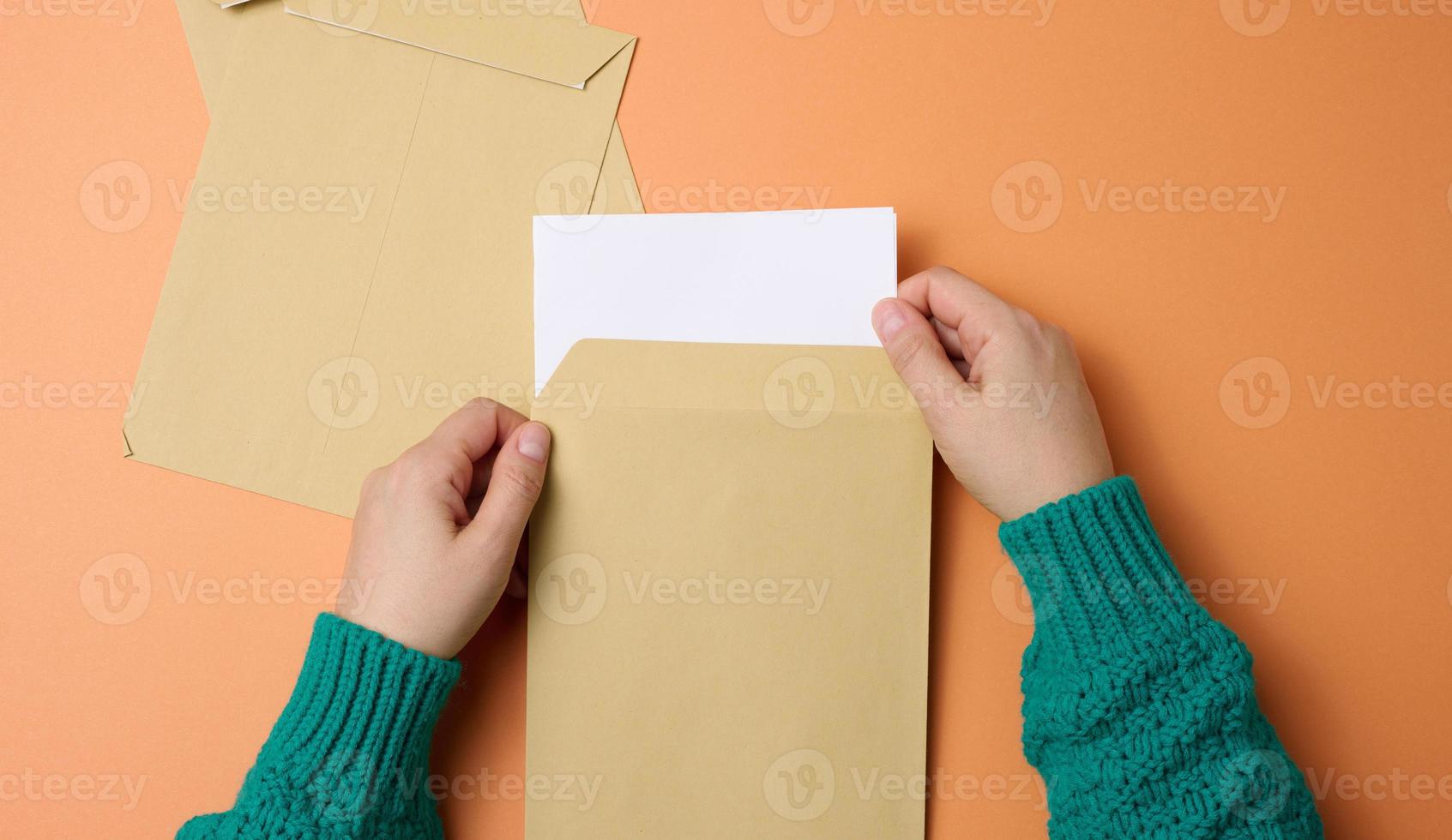 weibliche hand hält papierumschläge auf orangefarbenem hintergrund, draufsicht. Korrespondenz foto