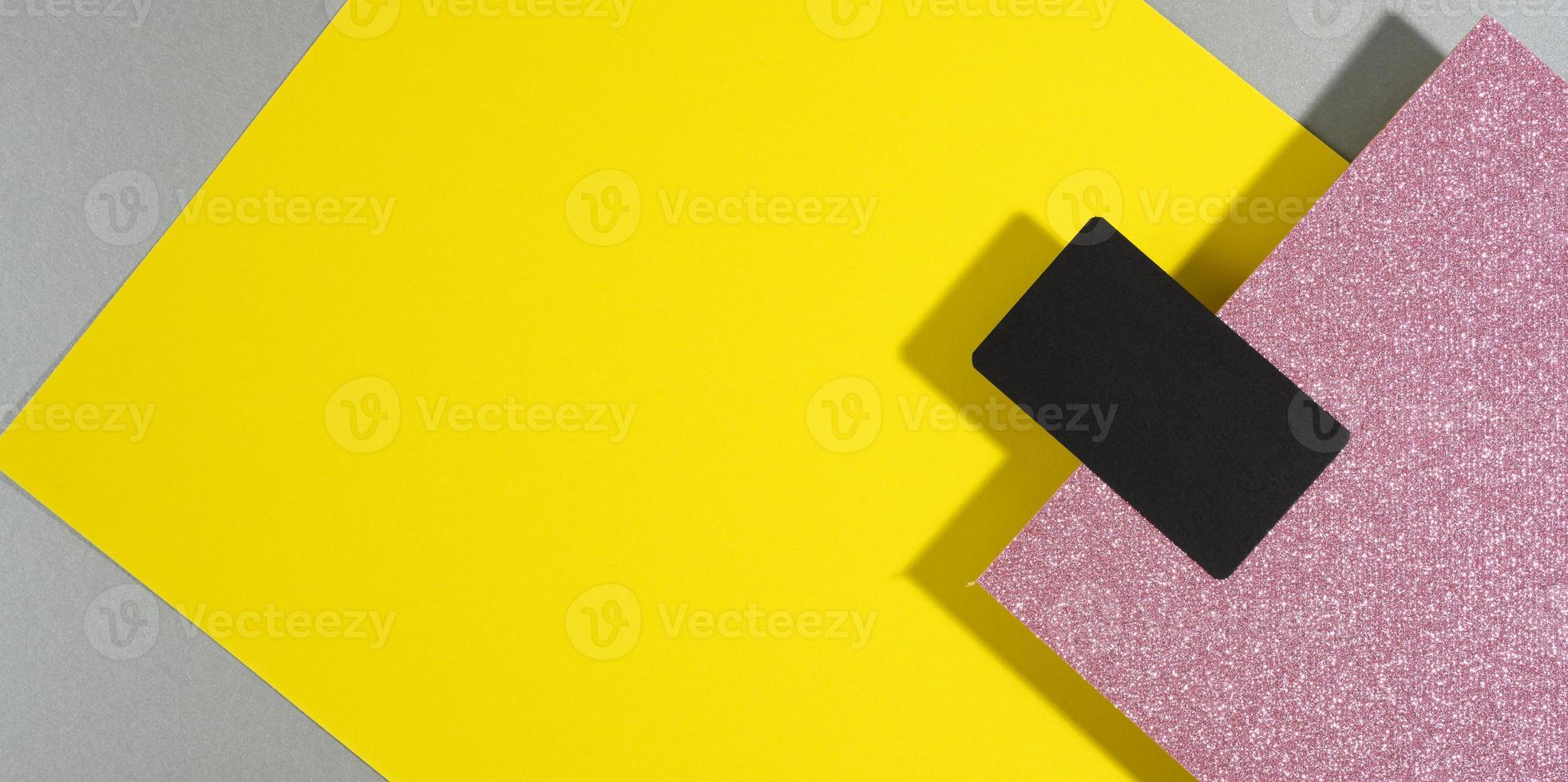leere schwarze rechteckige visitenkarte auf einem kreativen hintergrund aus papierbögen mit schatten, grauem hintergrund und gelben blättern foto