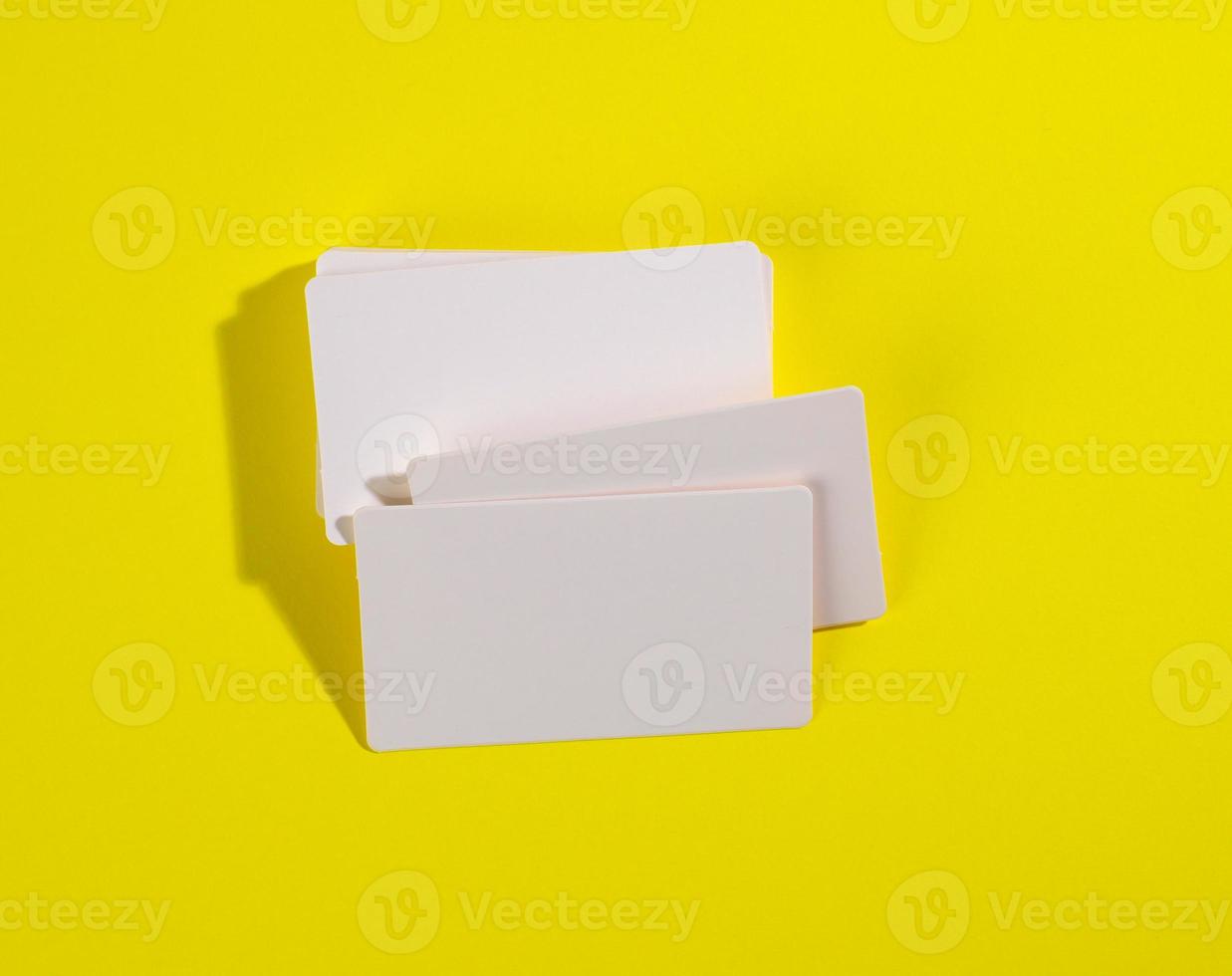 ein Stapel weißer rechteckiger Visitenkarten auf gelbem Hintergrund, Firmenlogo, Adresse foto