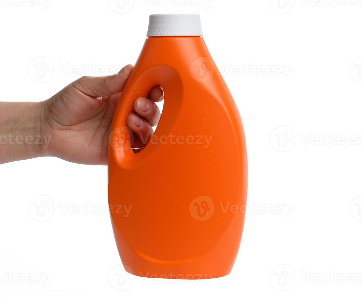 weibliche hand, die orangefarbene plastikflasche für flüssiges waschmittel hält foto