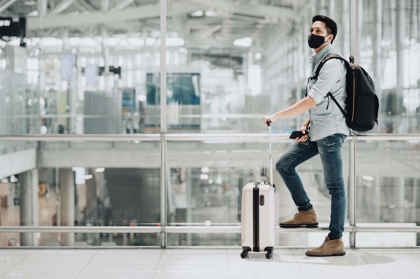 Mann trägt Maske und Rucksack am Flughafen foto