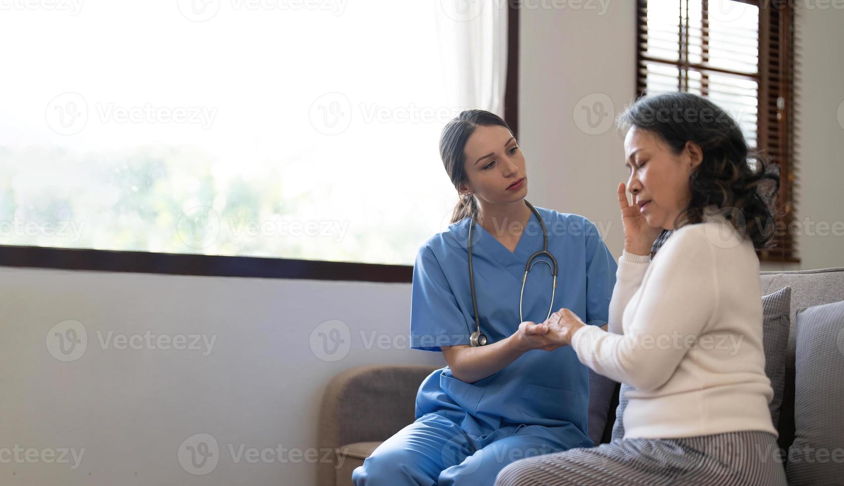 Junge Ärztin, die sich zu einer älteren Patientin vorbeugt, die ihre Hand in den Handflächen hält. unterstützende ermutigende alte Person. foto