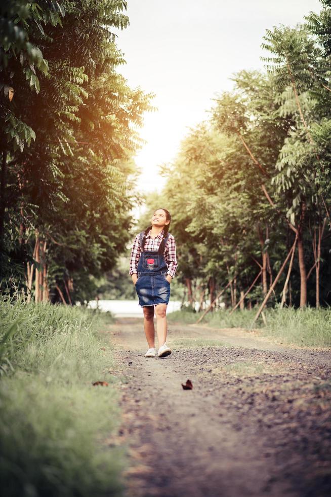 junges glückliches Mädchen, das in einem Wald im Sommer geht foto