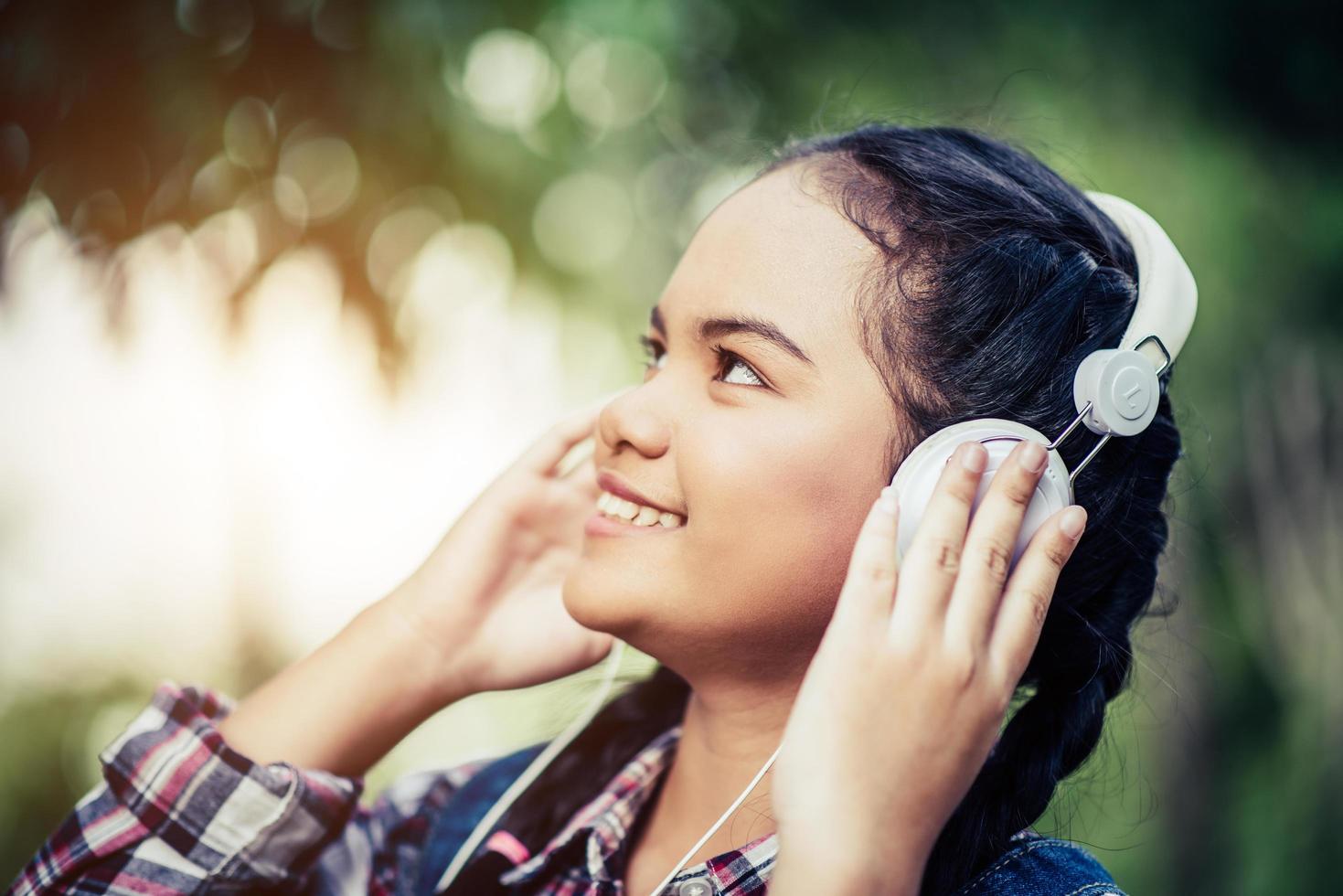 junges glückliches Mädchen, das Musik mit ihren Kopfhörern hört foto