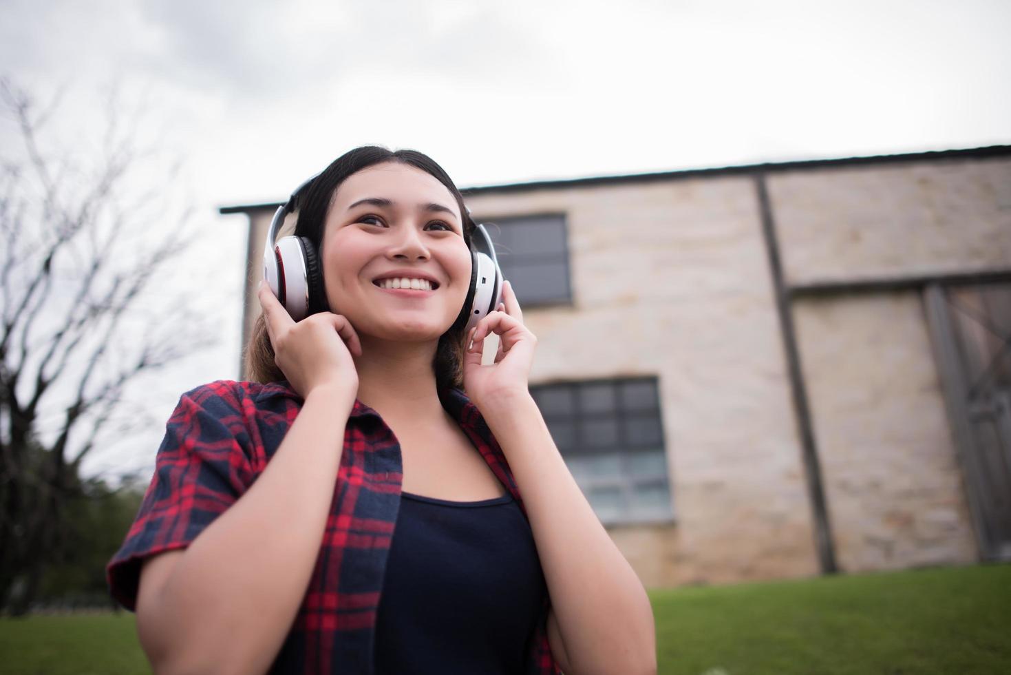 Nahaufnahme der jungen Hipsterfrau, die Musik im Freien hört foto