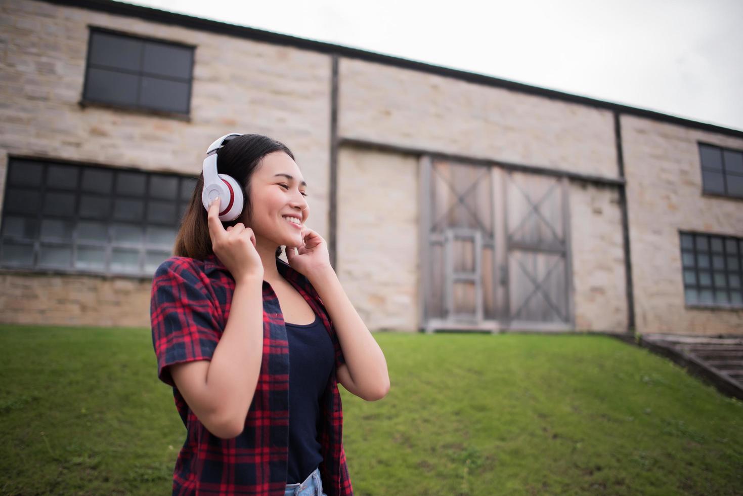 Nahaufnahme der jungen Hipsterfrau, die Musik im Freien hört foto