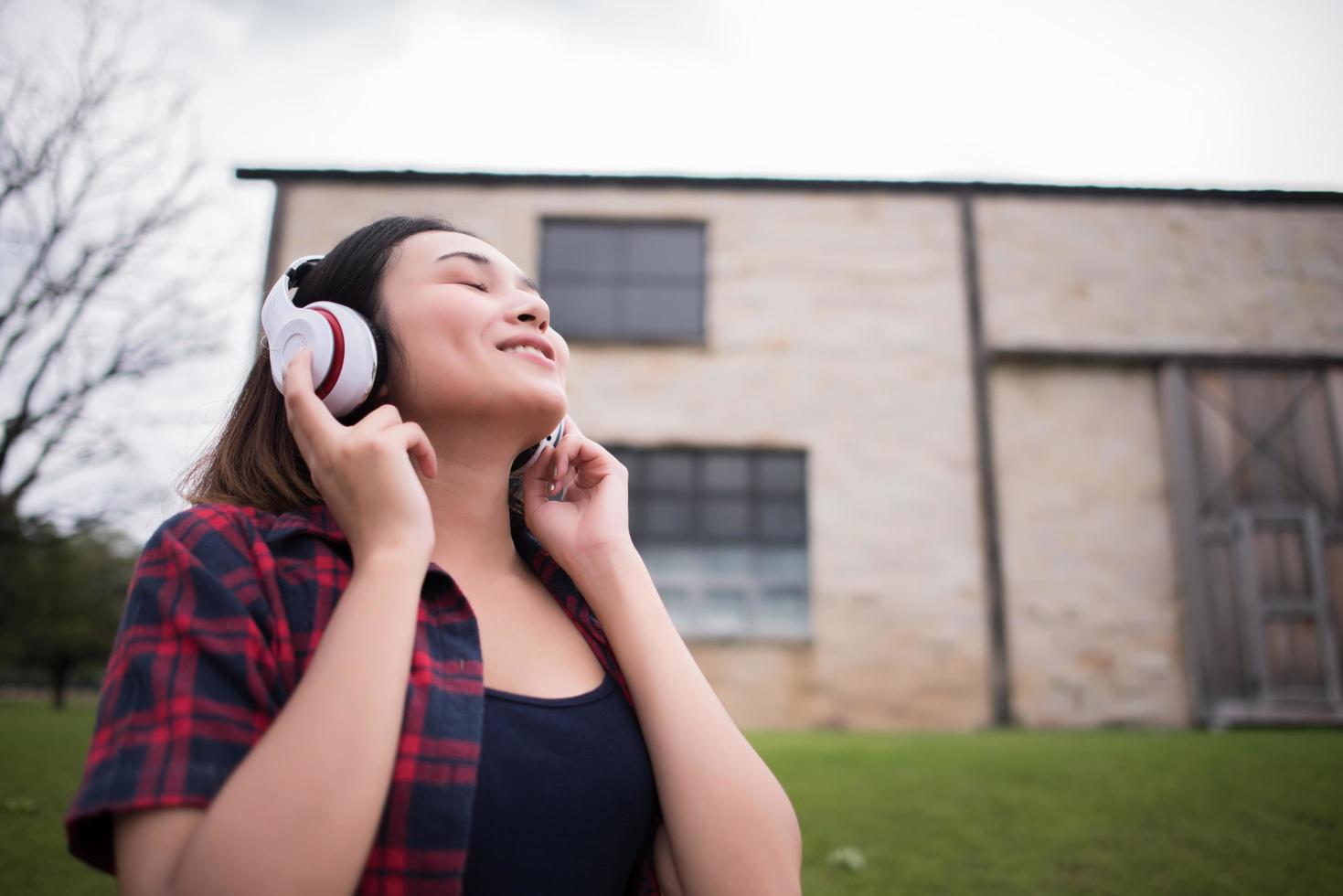 Nahaufnahme der jungen Hipsterfrau, die Musik im Freien hört foto