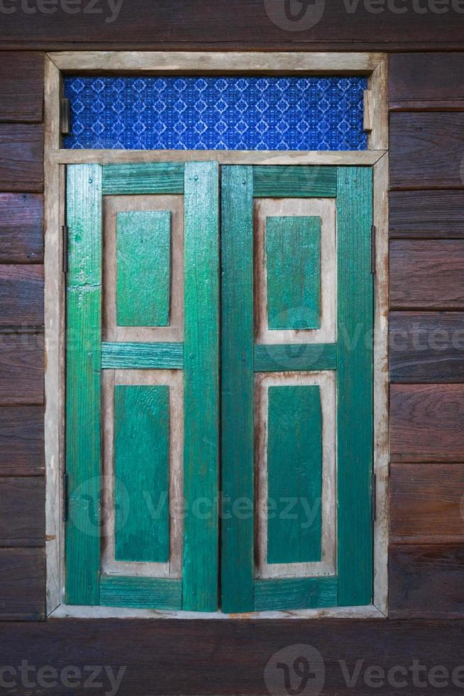 Holzweinlesefenster mit grünen Fensterläden an der Holzwand foto