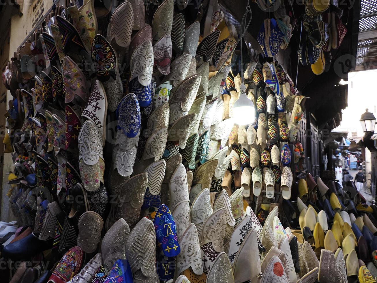 bunte handgefertigte lederpantoffeln warten auf kunden im shop in fes, neben gerbereien, marokko foto