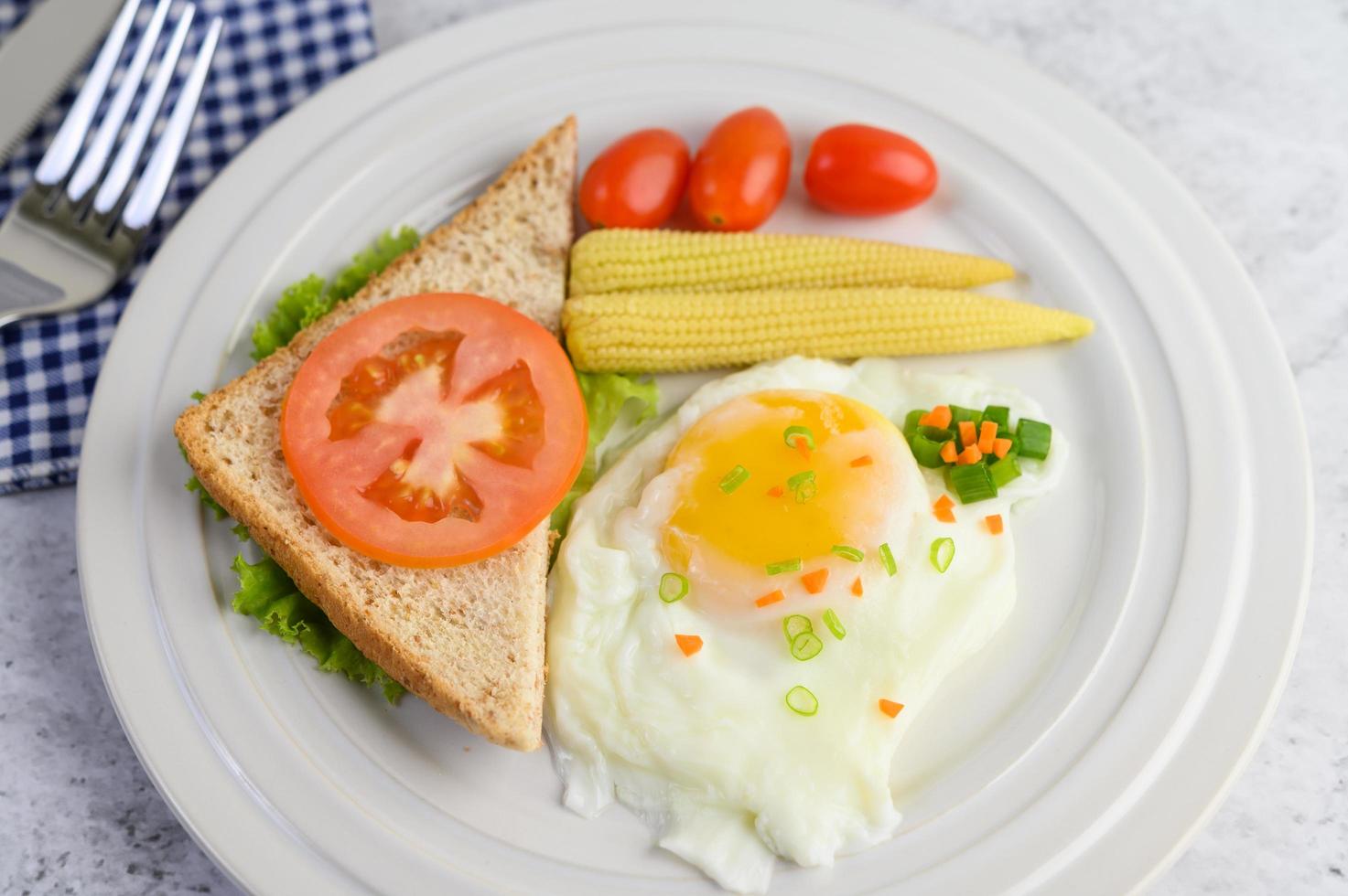 ein Spiegelei mit Toast, Karotten, Babymais und Frühlingszwiebeln foto