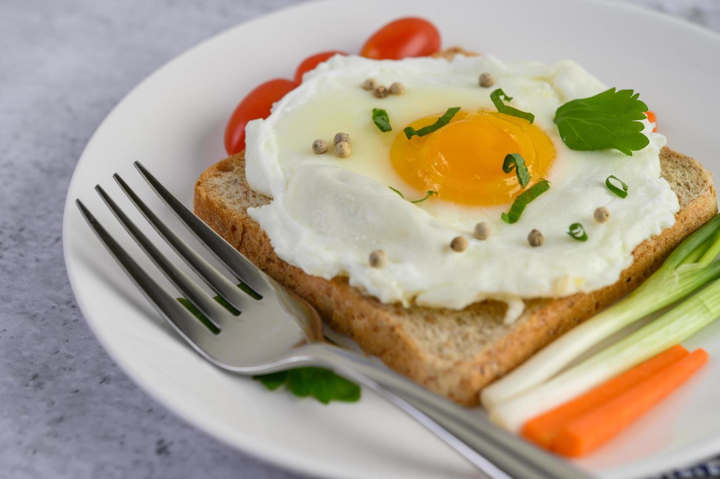 ein Spiegelei auf Toast mit Pfeffersamen, Karotten und Frühlingszwiebeln foto