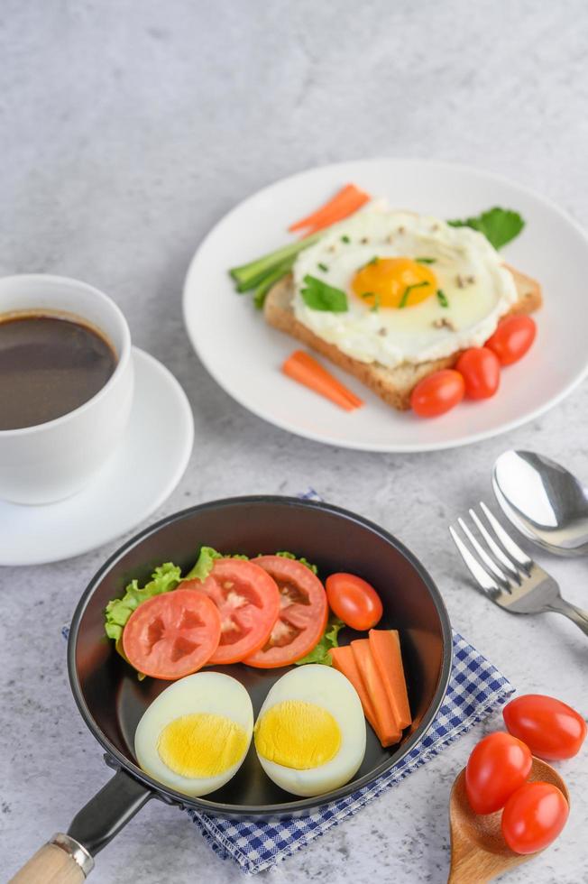 gekochte Eier, Karotten und Tomaten mit Löffel und Kaffeetasse foto