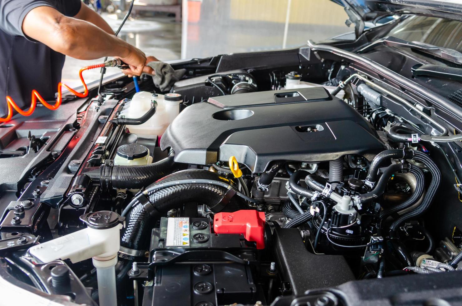 Mechaniker, der den Automotor reinigt foto