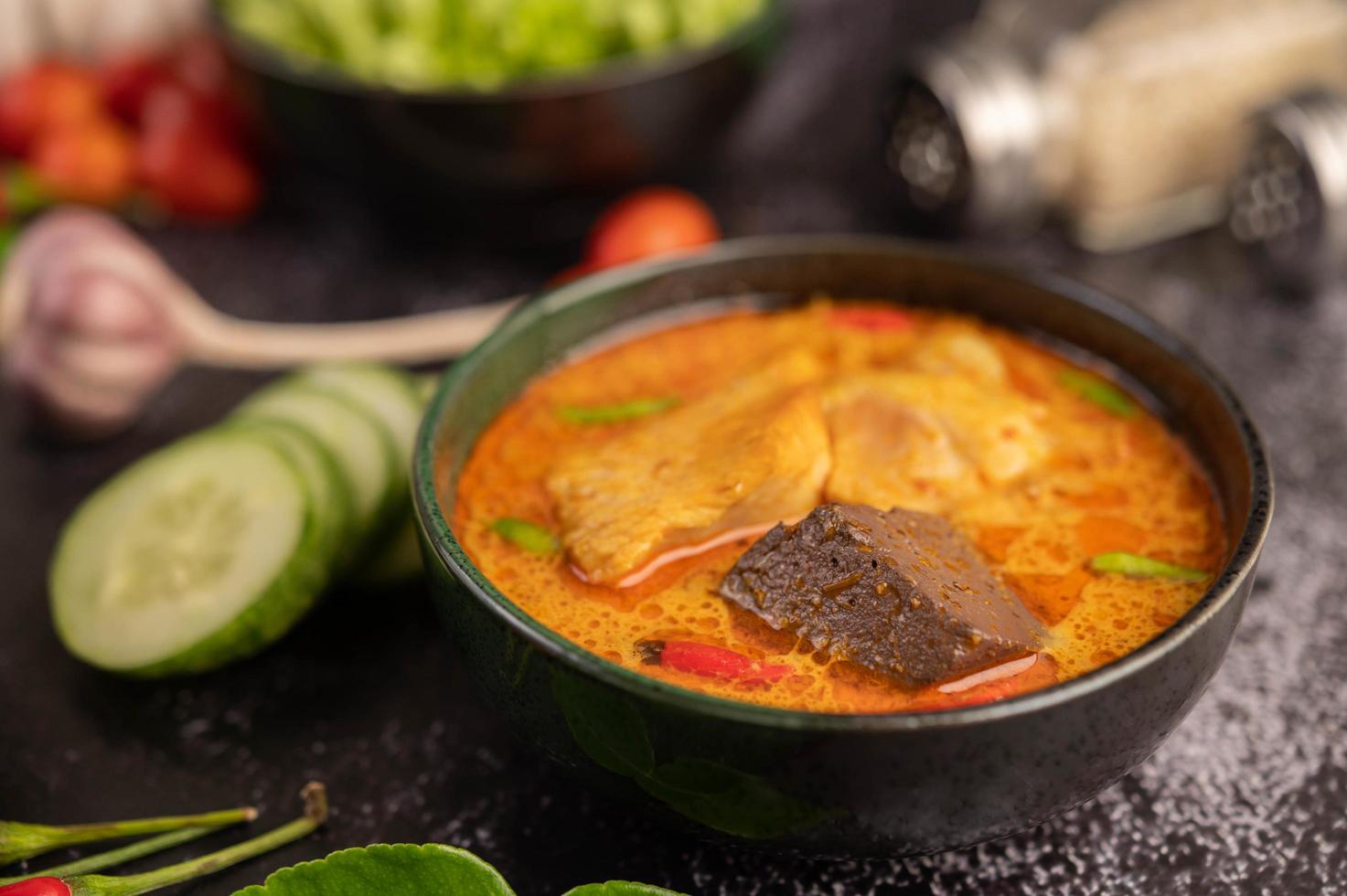 Hühnercurry in einer schwarzen Tasse mit Knoblauch und Paprika foto