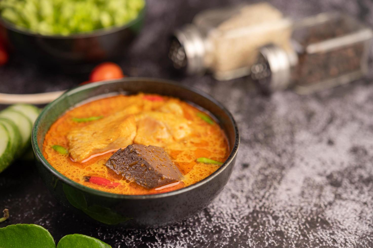 Hühnercurry in einer schwarzen Tasse mit Knoblauch und Paprika foto