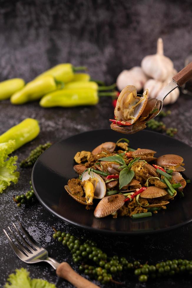 Muscheln mit Currypulver auf einem schwarzen Teller gebraten foto