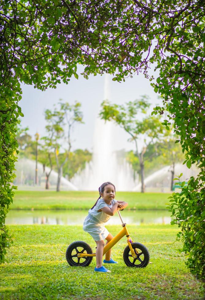 kleines Mädchen, das ein Laufrad im Park fährt foto