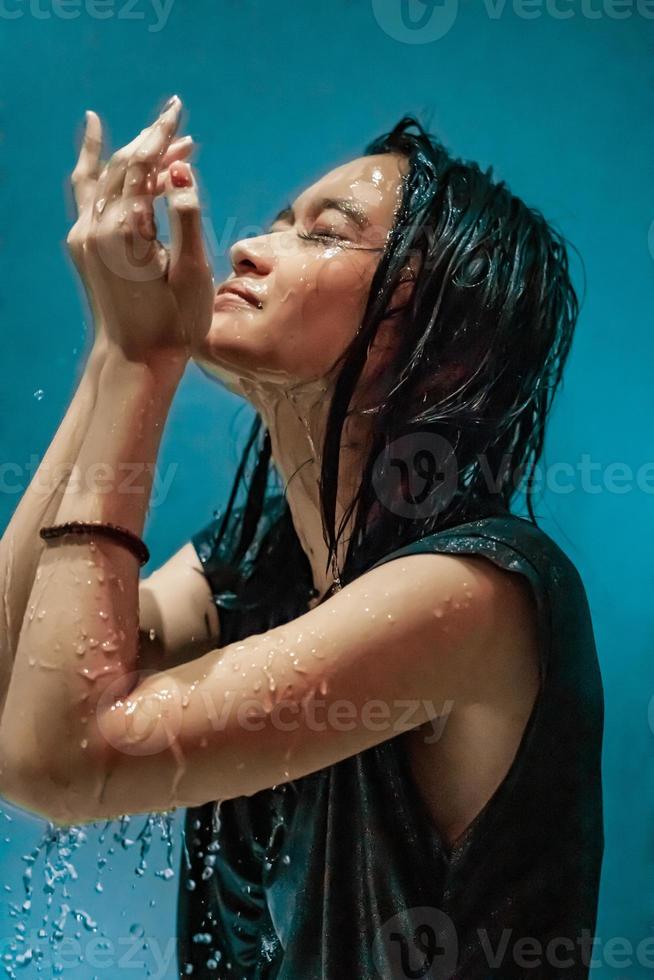 Porträt einer indonesischen Frau, die ein Bad in der Dusche nimmt, während sie ein schwarzes Kleid trägt foto
