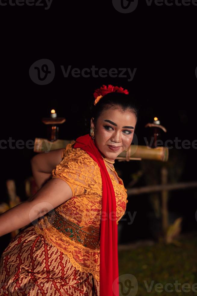 eine asiatische traditionelle tänzerin in einem orangefarbenen kleid mit rotem schal und make-up, die auf dem tanzfestival auftritt foto