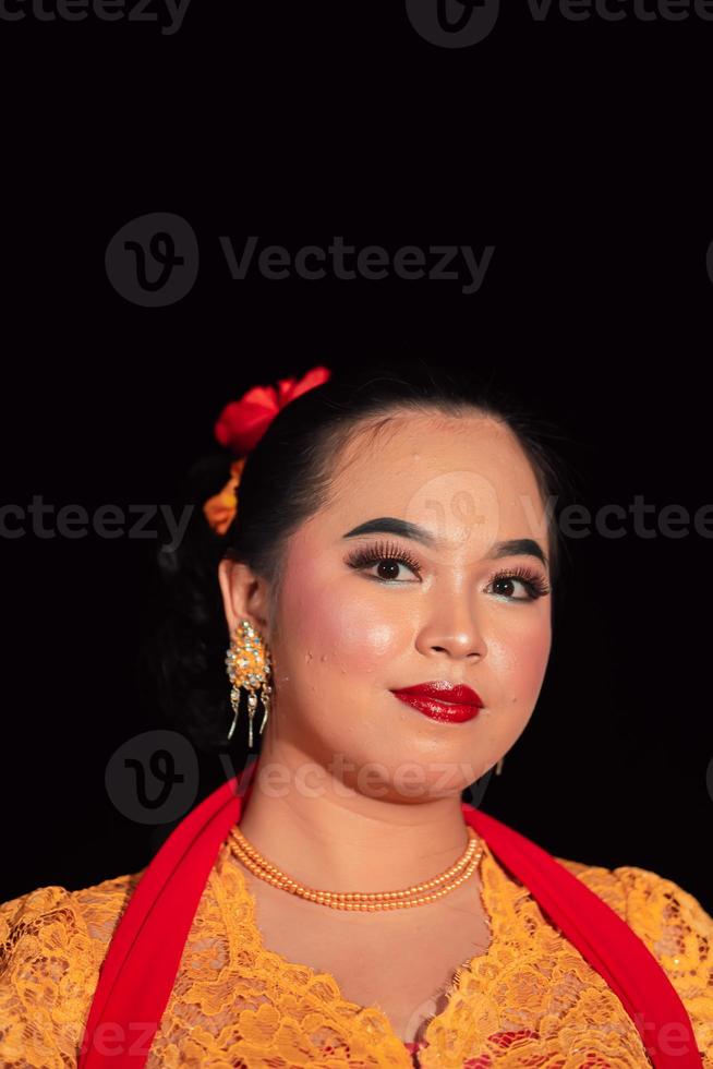 sundanesische frau, die nach der tanzvorstellung ein kurzes kleid und ein traditionelles gelbes kleid mit rotem schal und make-up trägt foto