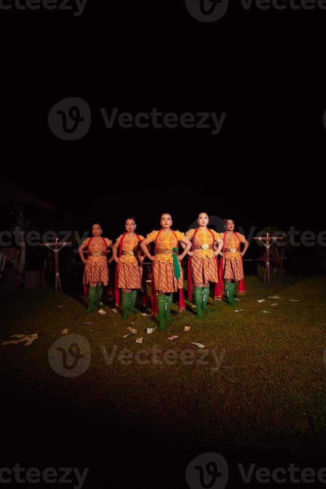 balinesische tänzer, die zusammen mit rotem schal und orangefarbenen kostümen auf der bühne stehen, nachdem sie den traditionellen tanz aufgeführt haben foto