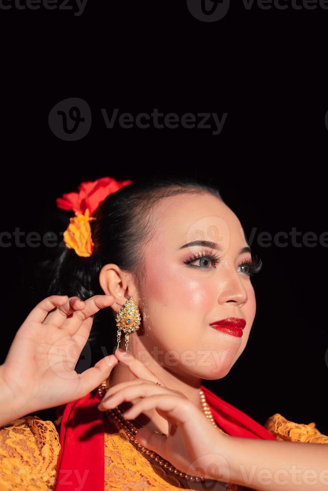 exotische javanische Frau, die schönes Make-up mit roten Lippen trägt, während sie ein traditionelles gelbes Kostüm und einen roten Schal trägt foto