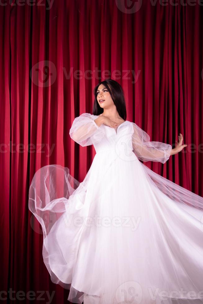 asiatische frau posiert in einem glamourösen hochzeitskleid mit fliegendem stoff aus dem kleid foto